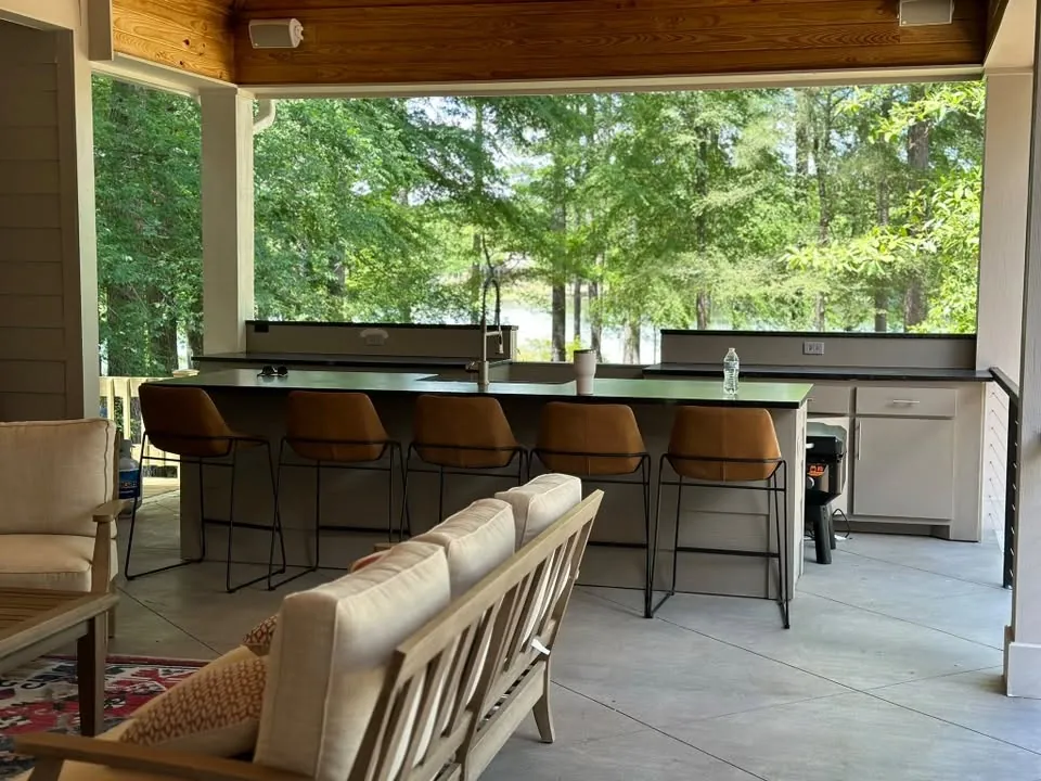 Covered outdoor kitchen with a long bar and lounge seating